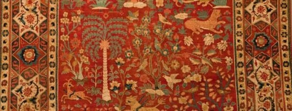 Traditional Bhadohi carpet with intricate floral and animal motifs, red background