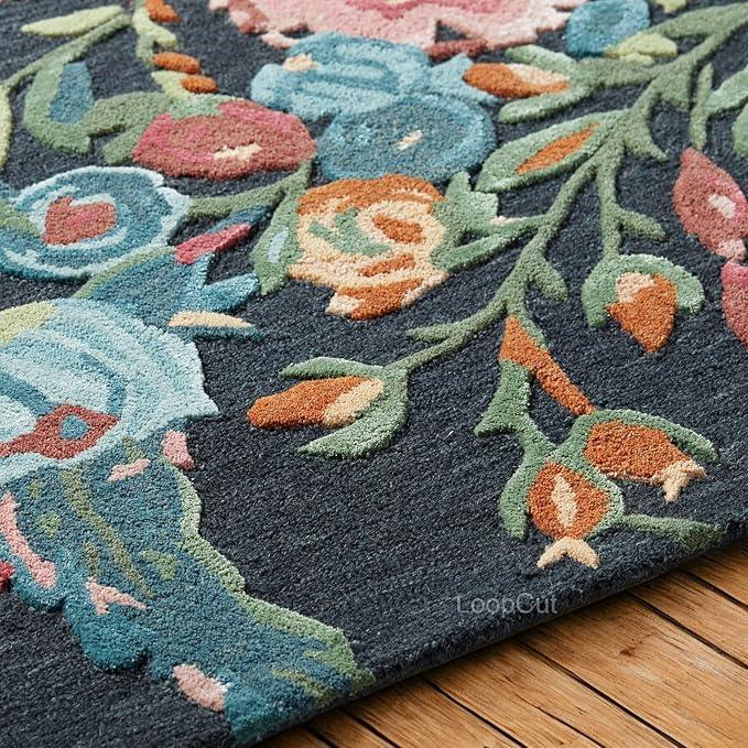 Black hand-tufted rug with colorful floral design on wooden floor from Bhadohi Carpets House