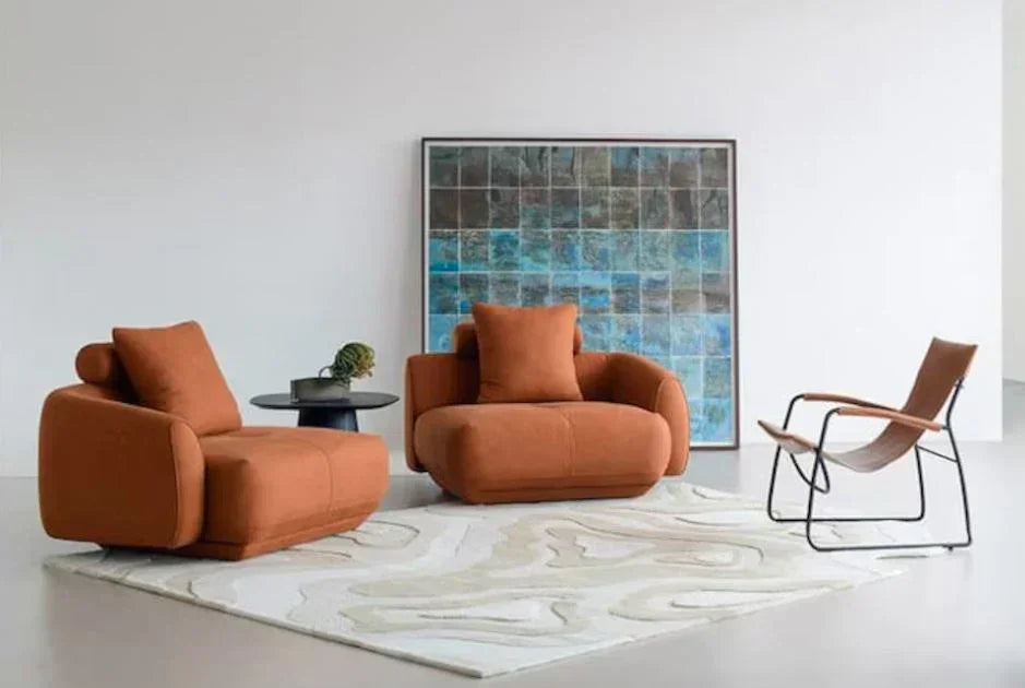 Modern living room with rust sofas, designer chair, and Bhadohi irregular carpet rug