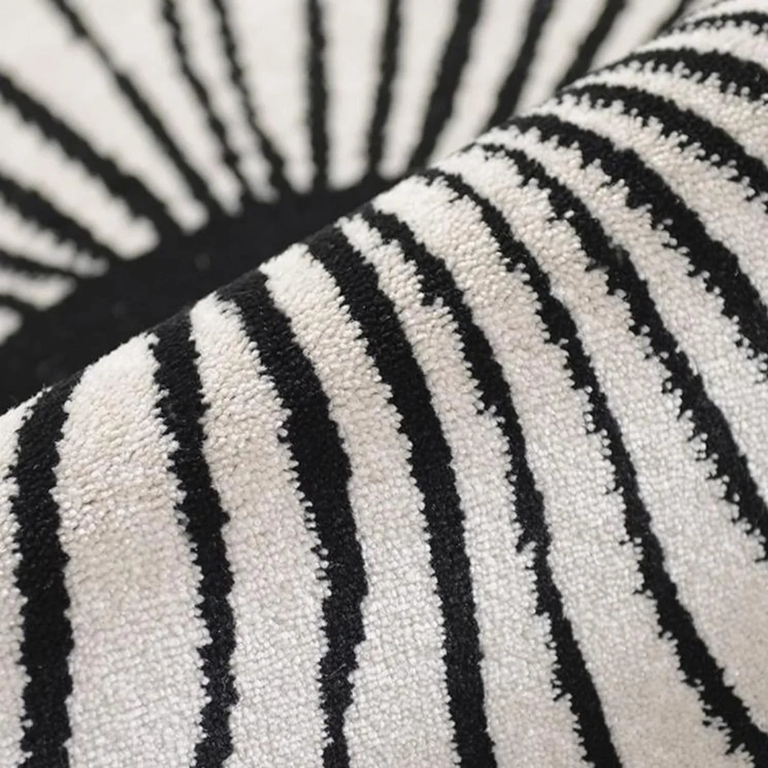 Close-up of round black and white wool carpet with bold striped pattern from Bhadohi Carpets House.