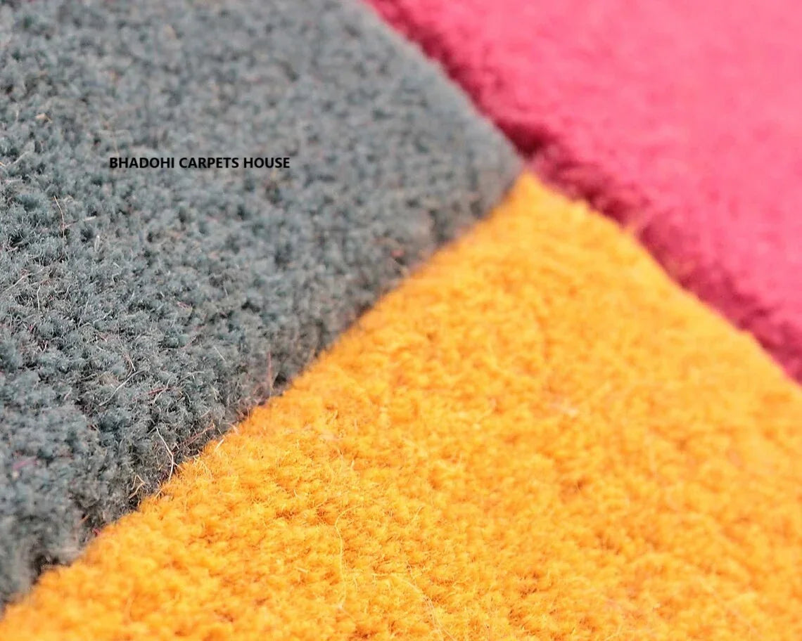 Close-up of colorful textured carpet rug with yellow, grey, and pink sections from Bhadohi Carpets House.