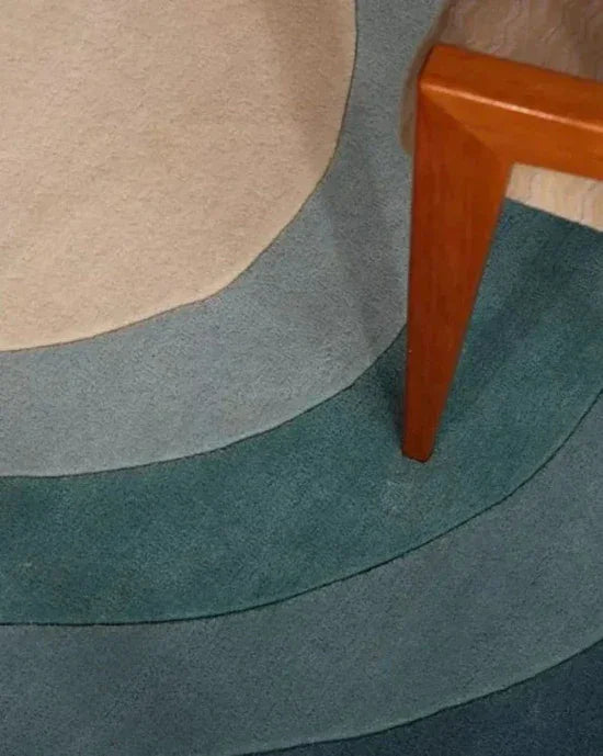 Modern irregular carpet with blue and beige curves, wooden furniture leg, Bhadohi Carpets House