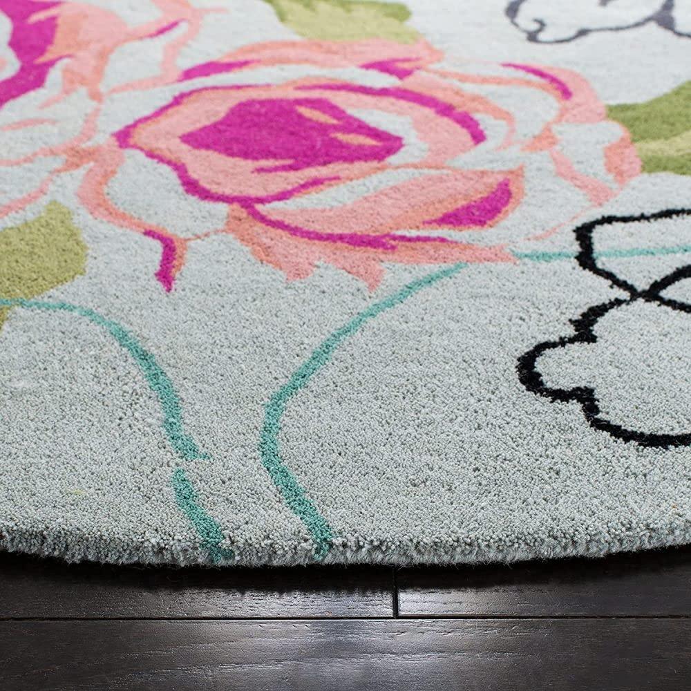 Ivory round wool carpet with colorful floral design on dark wooden floor, Bhadohi Carpets House