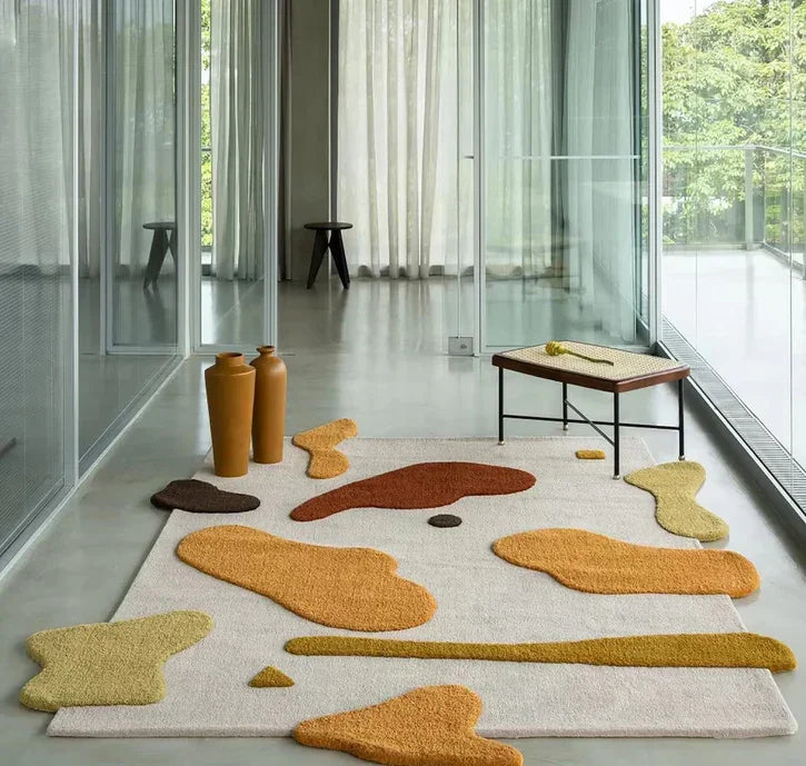 Modern living room with large glass windows, featuring a Bhadohi Carpets House abstract rug in beige, yellow, and orange tones, with minimalist decor.