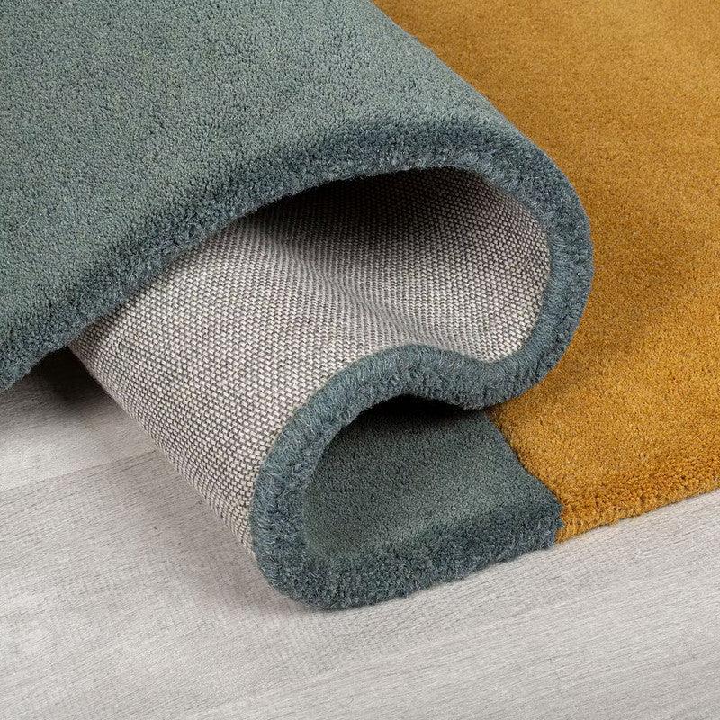 Modern dual-tone irregular carpet rug with green and mustard colors on a light floor