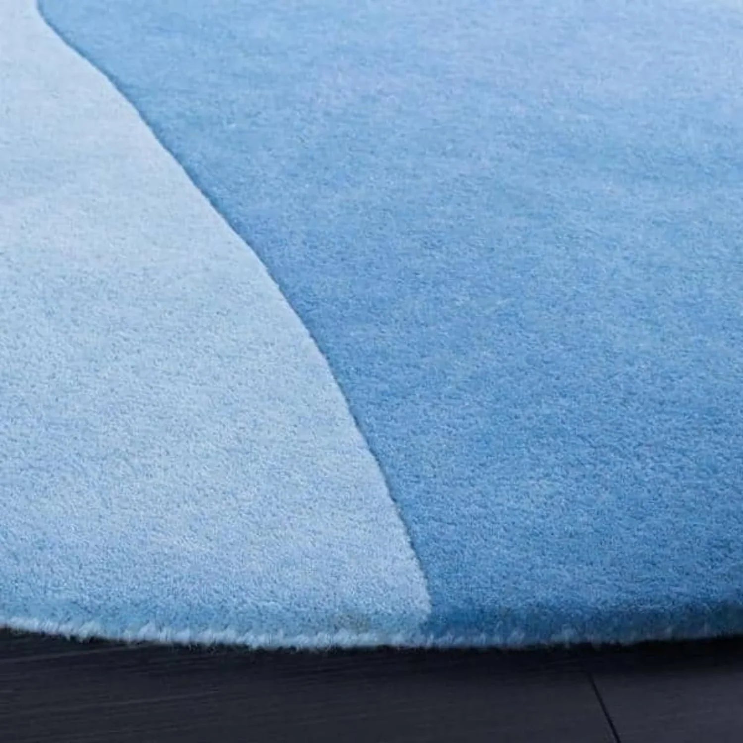 Round blue wool carpet rug with abstract design on a dark floor, Bhadohi Carpets House