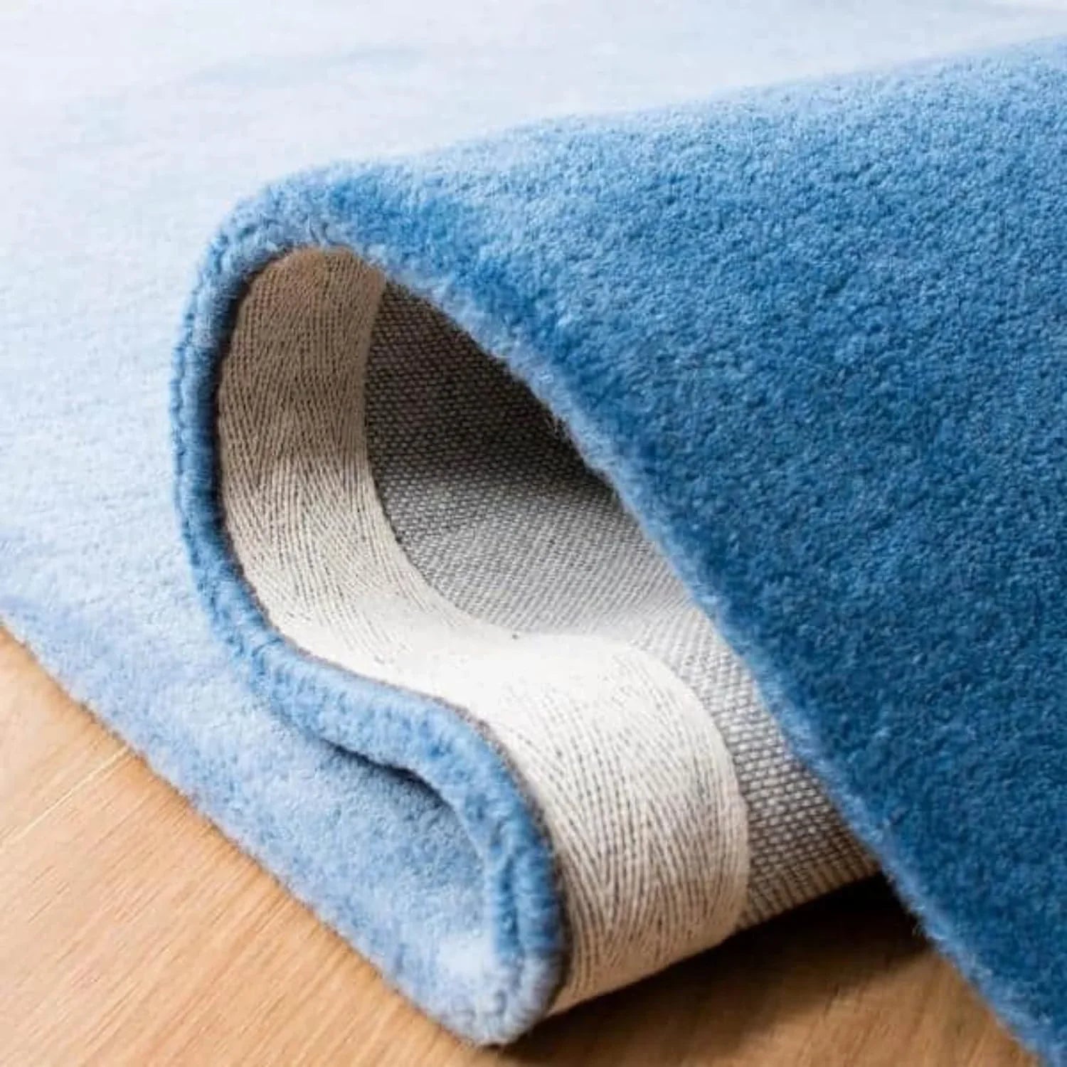 Close-up of a blue round wool carpet rug by Bhadohi Carpets House on wooden floor