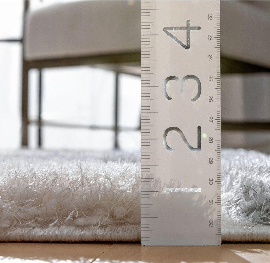 Close-up of plush shaggy rug with white fibers measured for pile height by transparent ruler, Bhadohi Carpets House