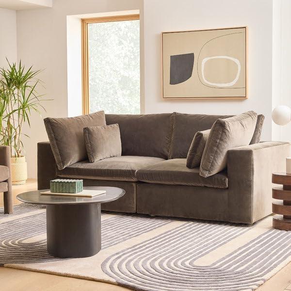 Modern living room with a geometric pattern rug from Bhadohi Carpets House, grey sofa, and round coffee table.