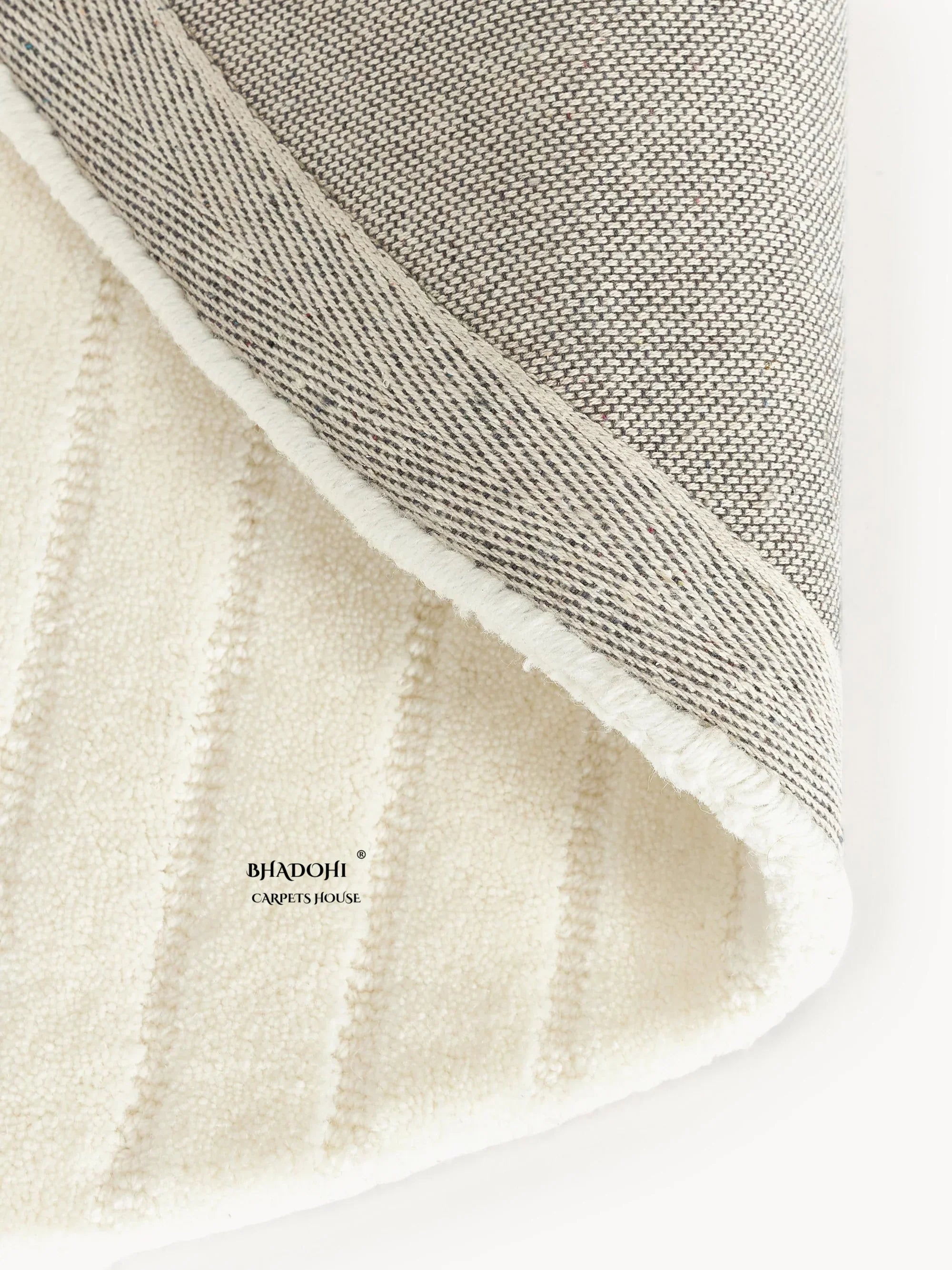 Close-up of Bhadohi Carpets House premium wool rug showing textured cream surface and grey border.