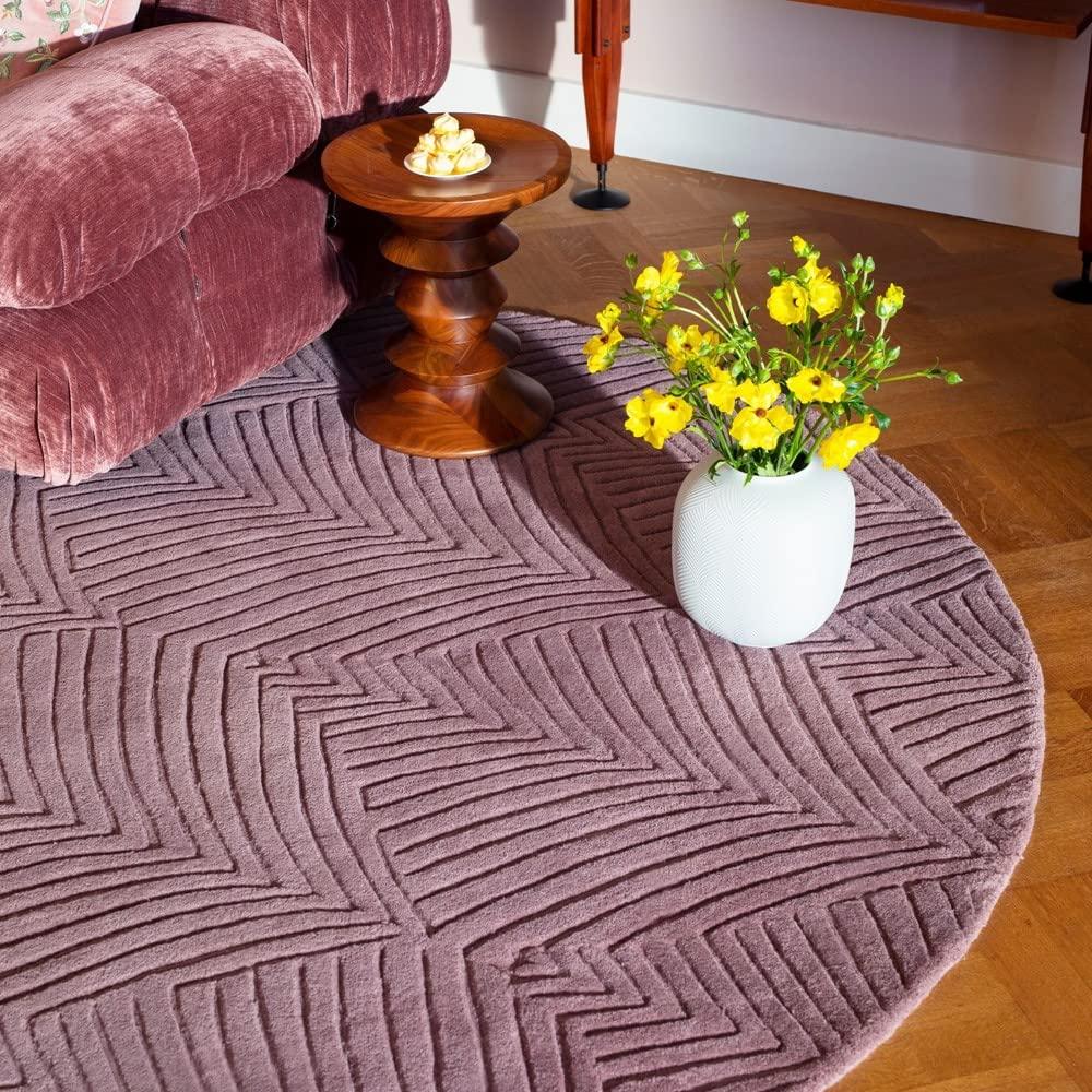 Round purple wool carpet with geometric pattern, velvet sofa, and flower vase, Bhadohi Carpets House