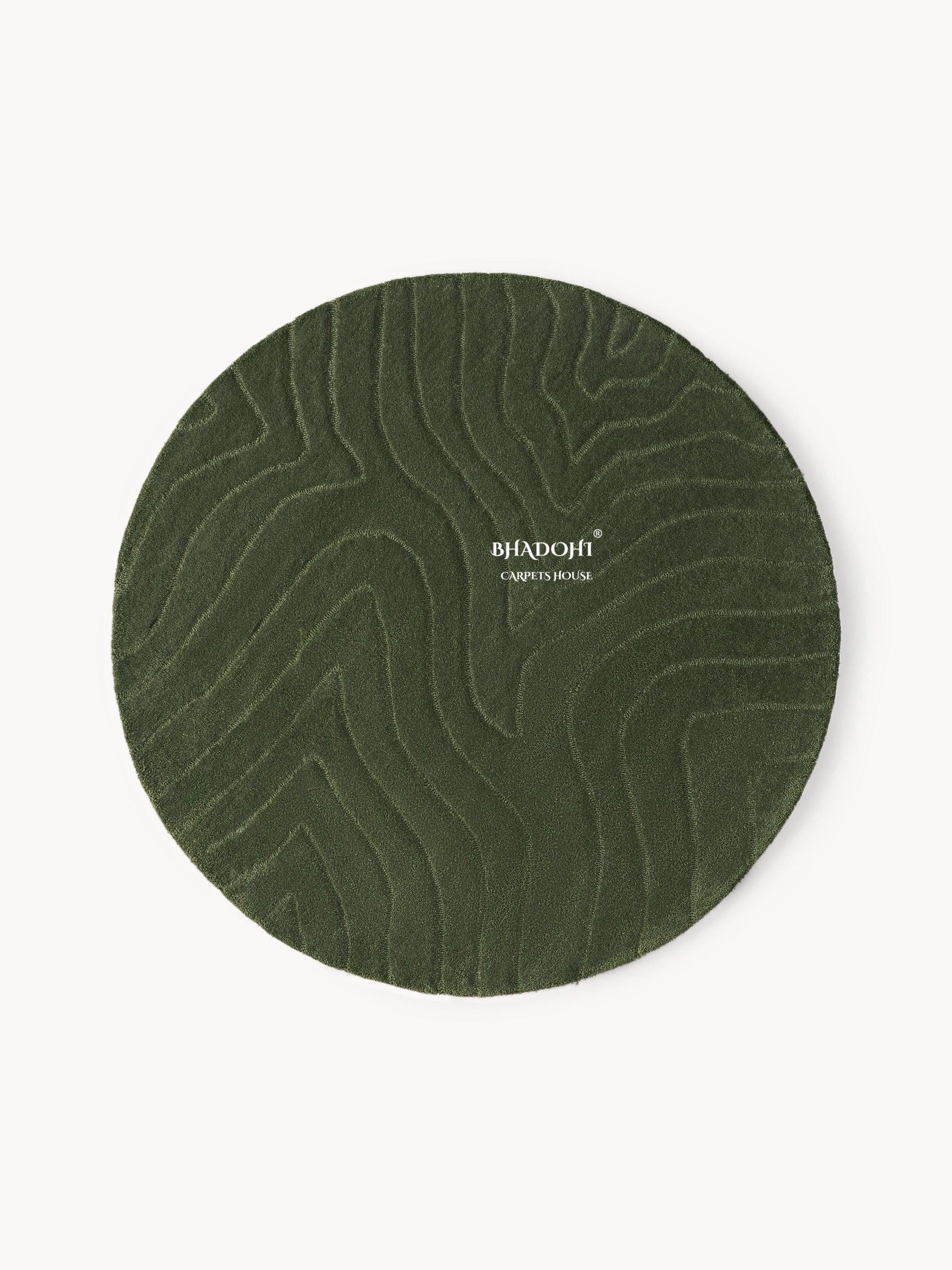 Round wool carpet in deep green with subtle textured pattern, Bhadohi Carpets House logo