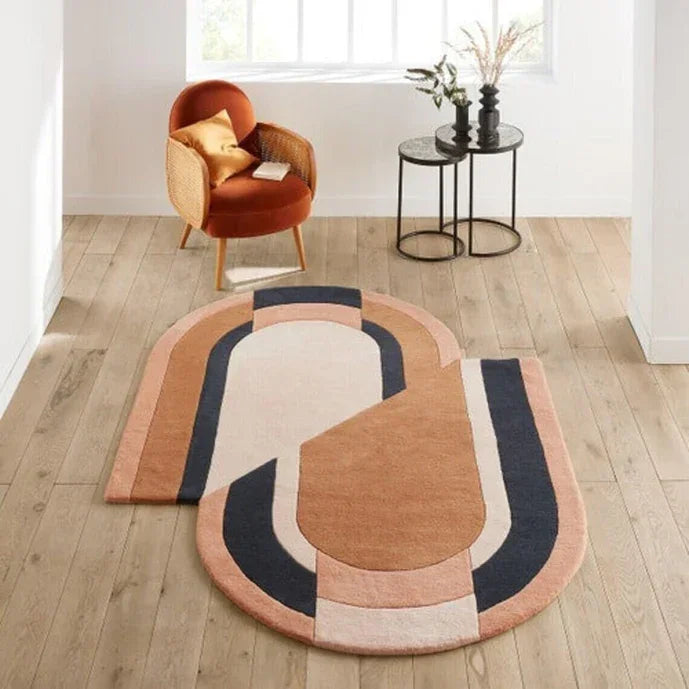 Modern geometric carpet rug in beige, navy, and peach tones on wood floor, Bhadohi Carpets House