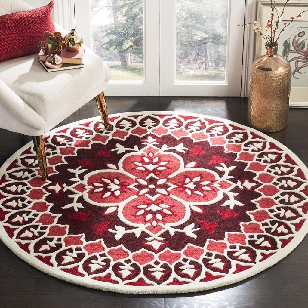 Red round wool carpet rug with intricate white pattern in modern living room, Bhadohi Carpets House
