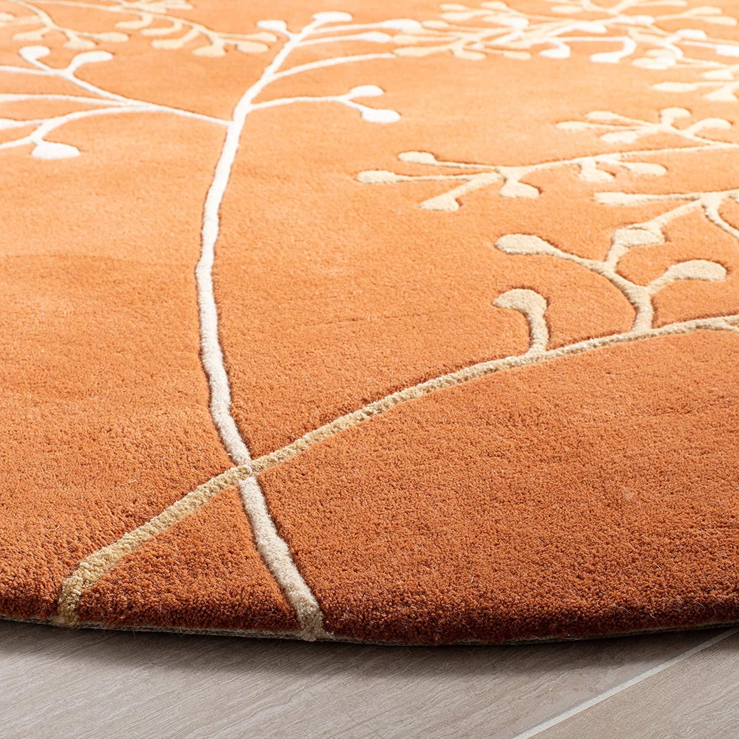 Round rust berry wool carpet rug with cream branch pattern on wooden floor, Bhadohi Carpets House