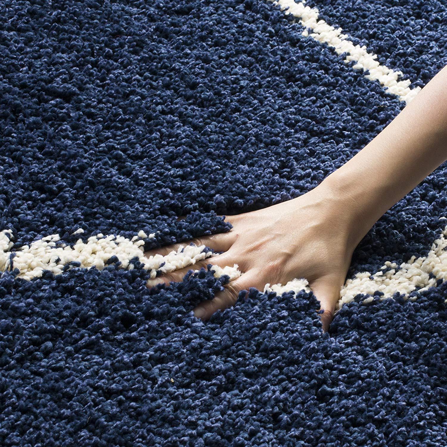 Hand touching soft shaggy navy blue and white carpet rug from Bhadohi Carpets House